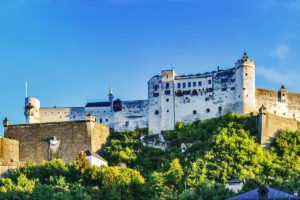 Fortress Hohensalzburg perched on green hill under blue sky