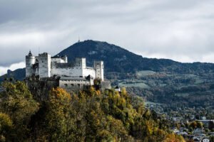 Fortress Hohensalzburg on hillside with autumn trees and distant mountains