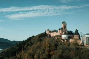 Haut-Koenigsbourg Castle perched on wooded hill under blue sky