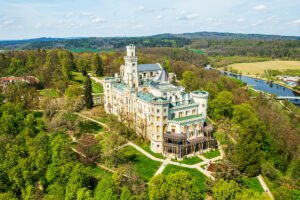 Aerial view of Hluboka Castle surrounded by green parkland and river