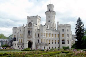 Hluboka Castle facade with manicured rose gardens and visitors