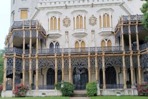 Facade of Hluboka Castle with ornate iron balconies and greenery
