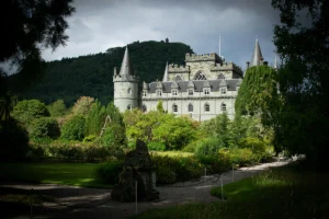 Inveraray Castle framed by gardens and wooded hills under dramatic sky