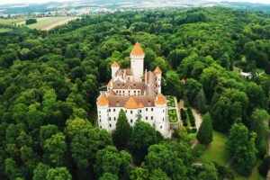 Aerial view of Konopiste Castle surrounded by dense green forest and manicured gardens
