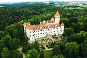 Aerial view of Konopiste Castle surrounded by dense forest and formal gardens