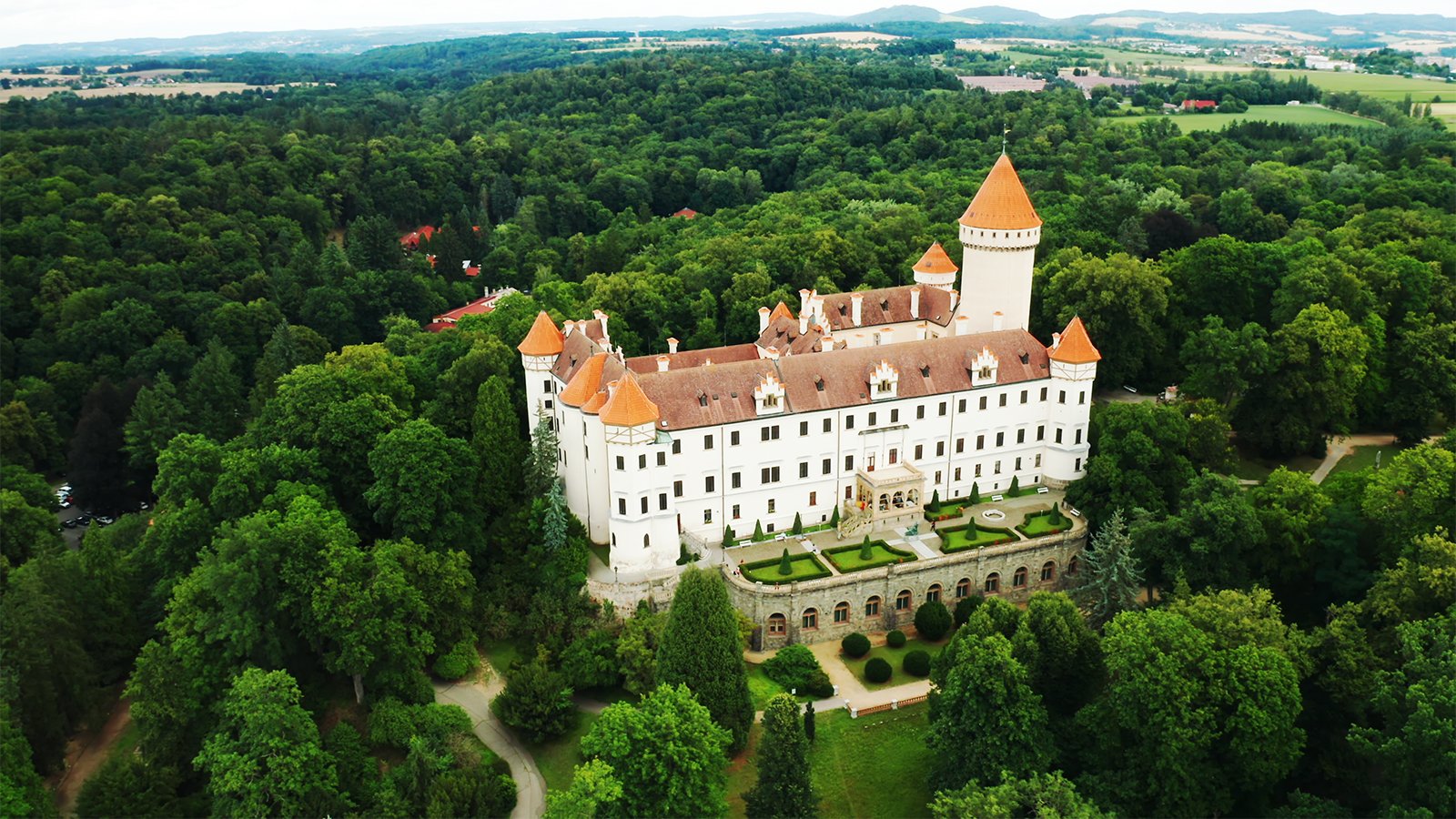 Aerial view of Konopiste Castle surrounded by dense green forest