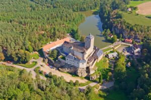 Aerial view of Kost Castle perched by forest lake