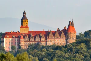 Ksiaz Castle on wooded hill with red roofs and tower