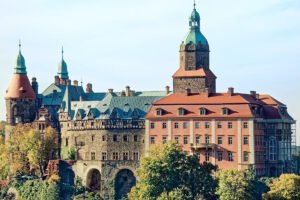 Ksiaz Castle perched on rocky ridge above lush trees and arches