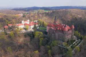 Aerial view of Ksiaz Castle with red roofs and surrounding forested hills