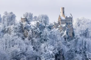 Lichtenstein Castle perched on snow-covered cliff amid frosted trees