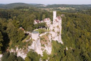 Aerial view of Lichtenstein Castle perched on limestone cliff surrounded by forest