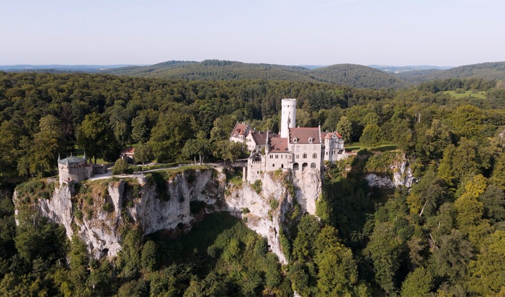 Aerial view of Lichtenstein Castle perched on limestone cliff amid dense forest