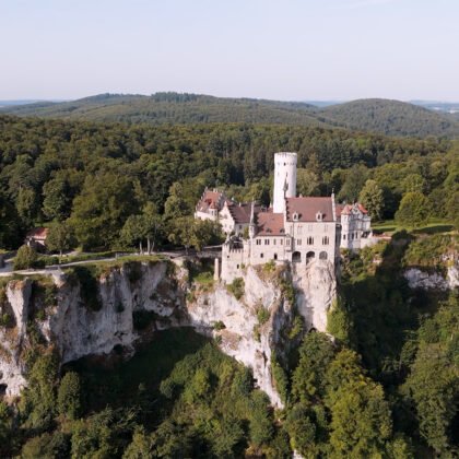 Aerial view of Lichtenstein Castle perched on limestone cliff amid dense forest