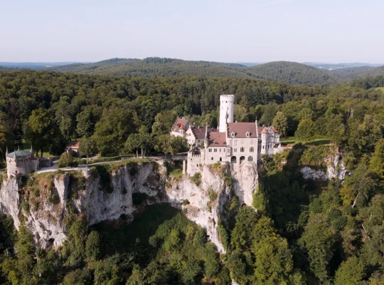 Aerial view of Lichtenstein Castle perched on limestone cliff amid dense forest