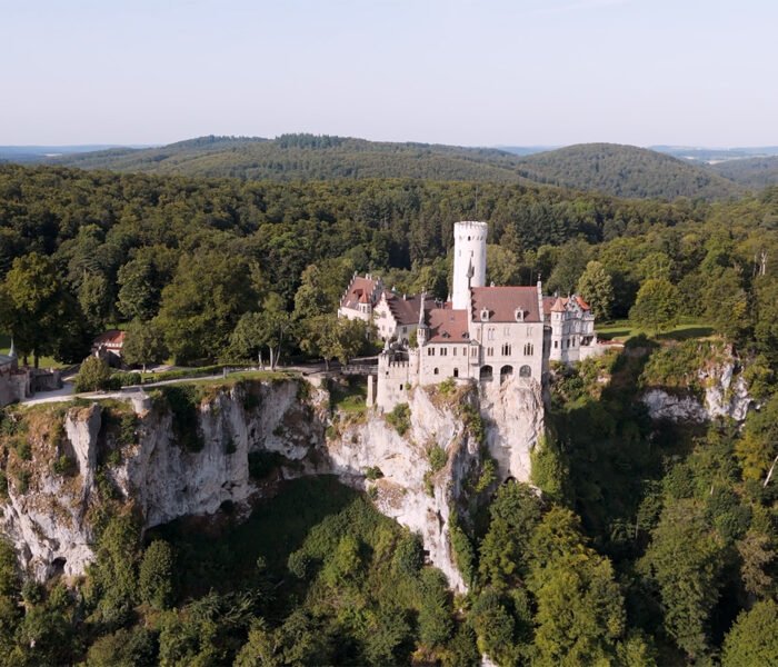 Aerial view of Lichtenstein Castle perched on limestone cliff amid dense forest