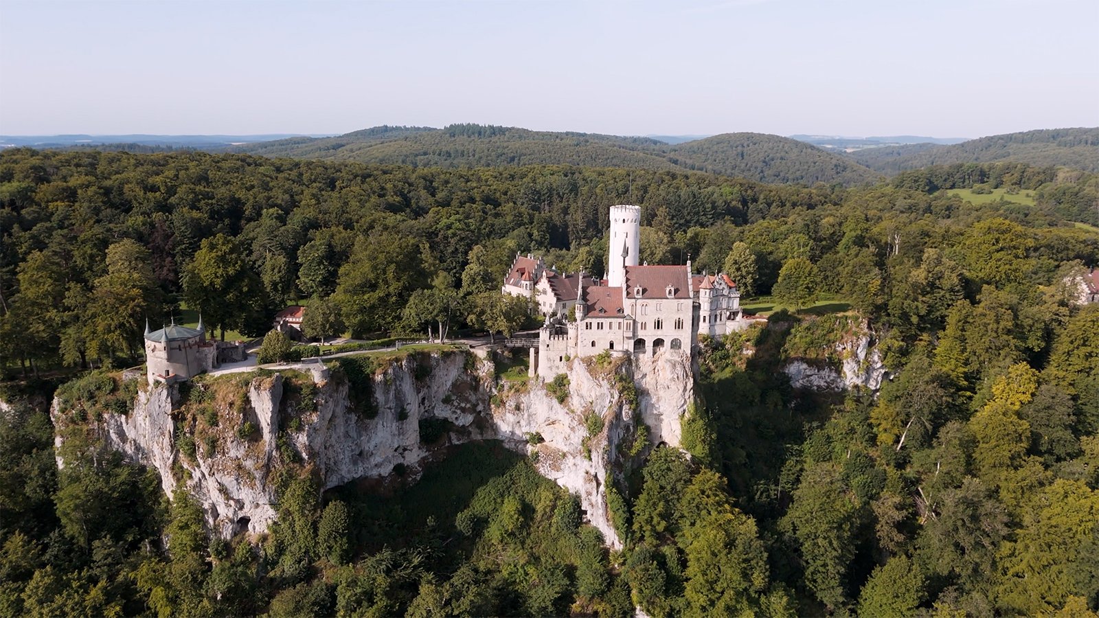 Aerial view of Lichtenstein Castle perched on limestone cliff amid dense forest