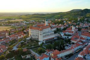 Aerial view of Mikulov Castle above red-roofed town and vineyards
