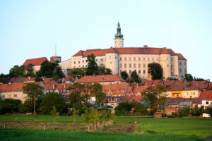 Mikulov Castle on hill above red-roofed town at sunset