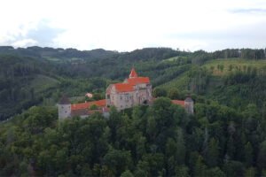 Aerial view of Pernstejn Castle atop forested hill