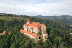Aerial view of Pernstejn Castle surrounded by trees and hills