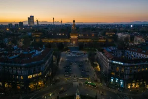 Aerial view of Sforzesco Castle at dusk with Milan skyline and fountain