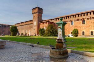sforzesco castle with fountain and pigeons in sunny courtyard