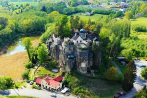 Aerial view of Sloup Castle atop sandstone pillars in a green valley