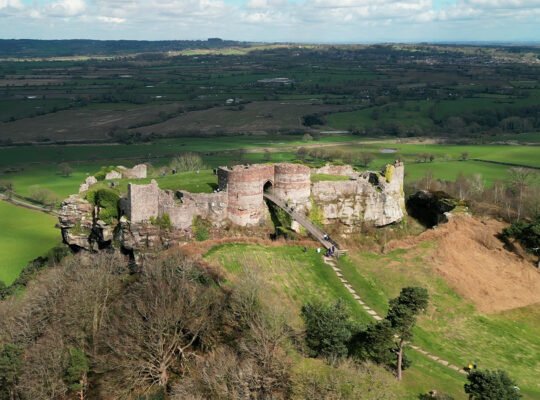 Aerial view of Beeston Castle ruins atop green Cheshire hills