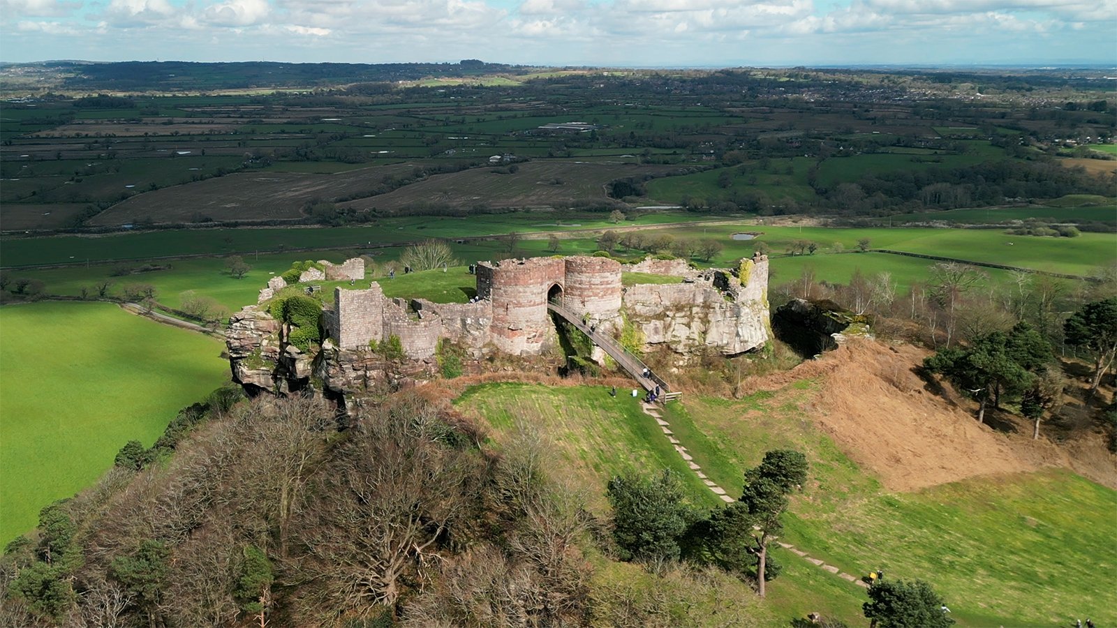 Aerial view of Beeston Castle ruins atop green Cheshire hills
