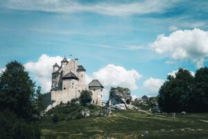 Bobolice Castle perched on rocky hill under blue sky