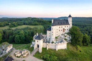 Aerial view of Bobolice Castle perched on rocky hill amid forest