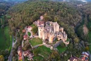 Aerial view of Bonaguil Castle on hilltop surrounded by forest