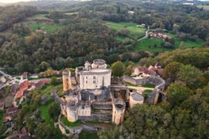 Aerial view of Bonaguil Castle surrounded by forest and village