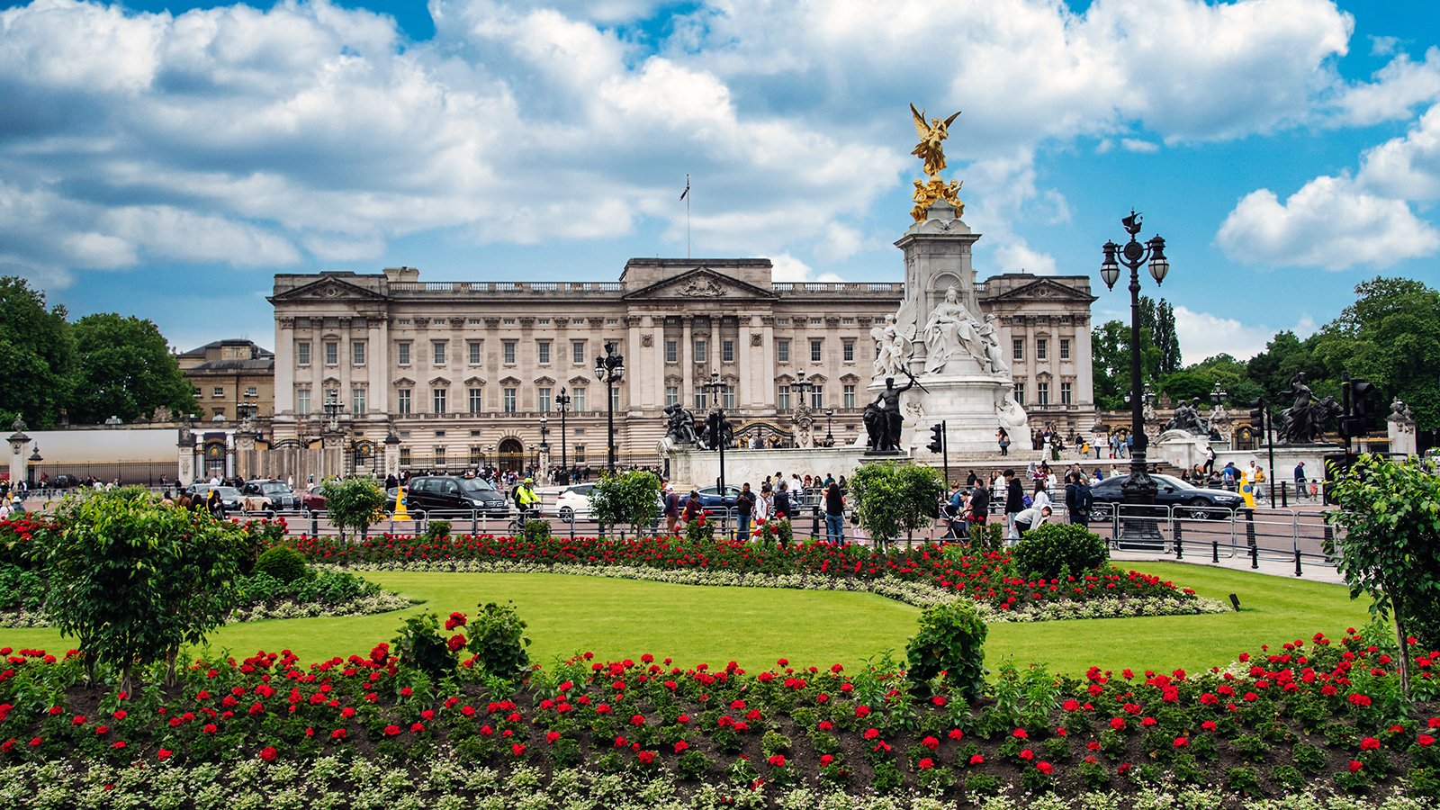 Buckingham Palace façade with Victoria Memorial and flowerbeds under blue sky
