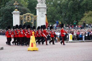 Guards in red tunics marching before Buckingham Palace gates during ceremony
