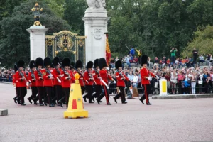 Guards in red tunics marching before Buckingham Palace gates during ceremony