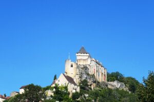Château de Castelnaud on hilltop overlooking valley under clear blue sky