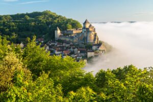 Château de Castelnaud perched above misty Dordogne valley at sunrise