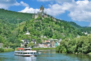 Cochem Castle on hill above river with tour boats