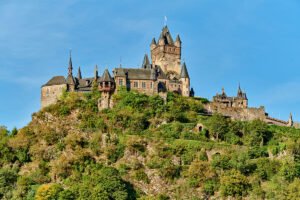 Cochem Castle perched on a green hill under blue sky