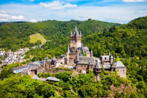 Aerial view of Cochem Castle atop wooded hill above Moselle town