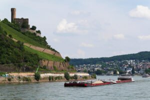 Ehrenfels Castle ruins on vineyard-covered Rhine slope beside river barge