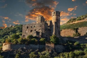 Ehrenfels Castle ruins perched above terraced vineyards at dramatic sunset