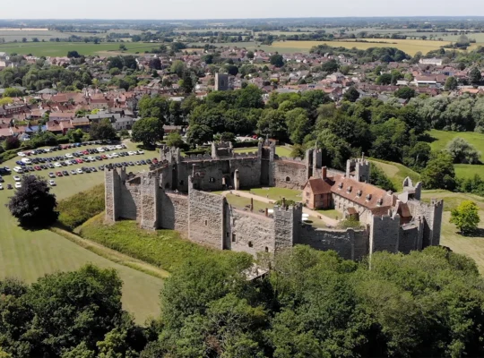 Castillo medieval visto desde el aire, con pueblo y campos verdes