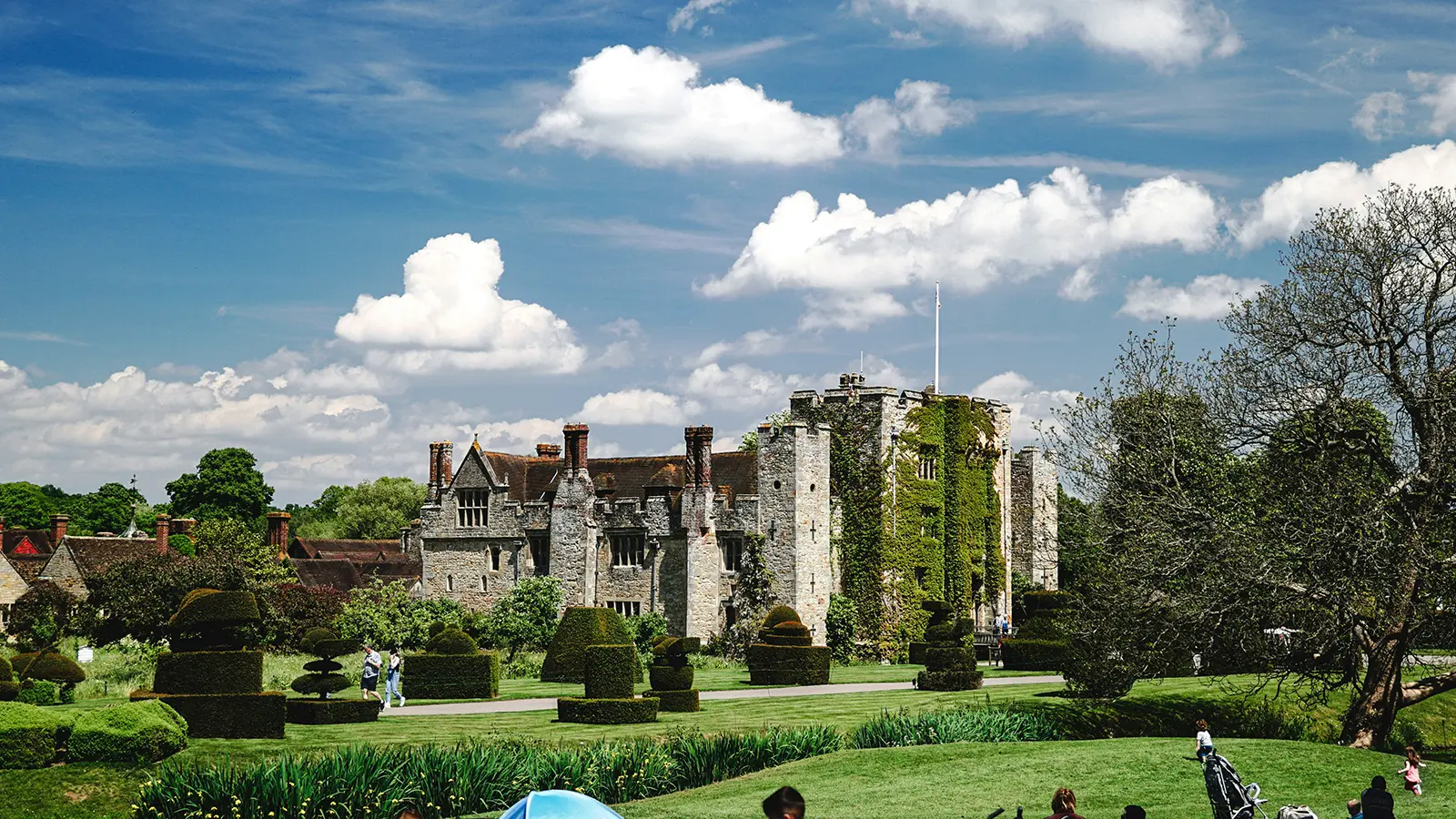 Hever Castle beside manicured gardens under a bright blue sky