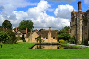 Hever Castle facade and reflecting lily pond under cloudy sky