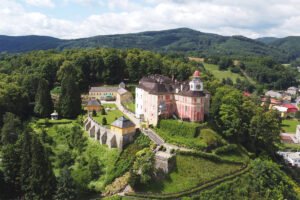 Aerial view of Jansky Vrch Castle atop lush hill with terraced gardens