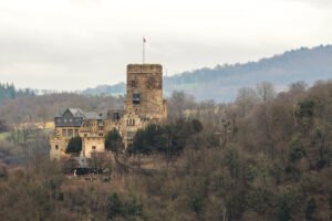 Lahneck Castle perched on wooded hillside under overcast sky