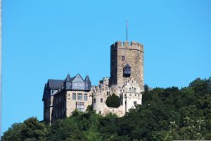 Lahneck Castle perched on wooded Rhine hill under clear blue sky